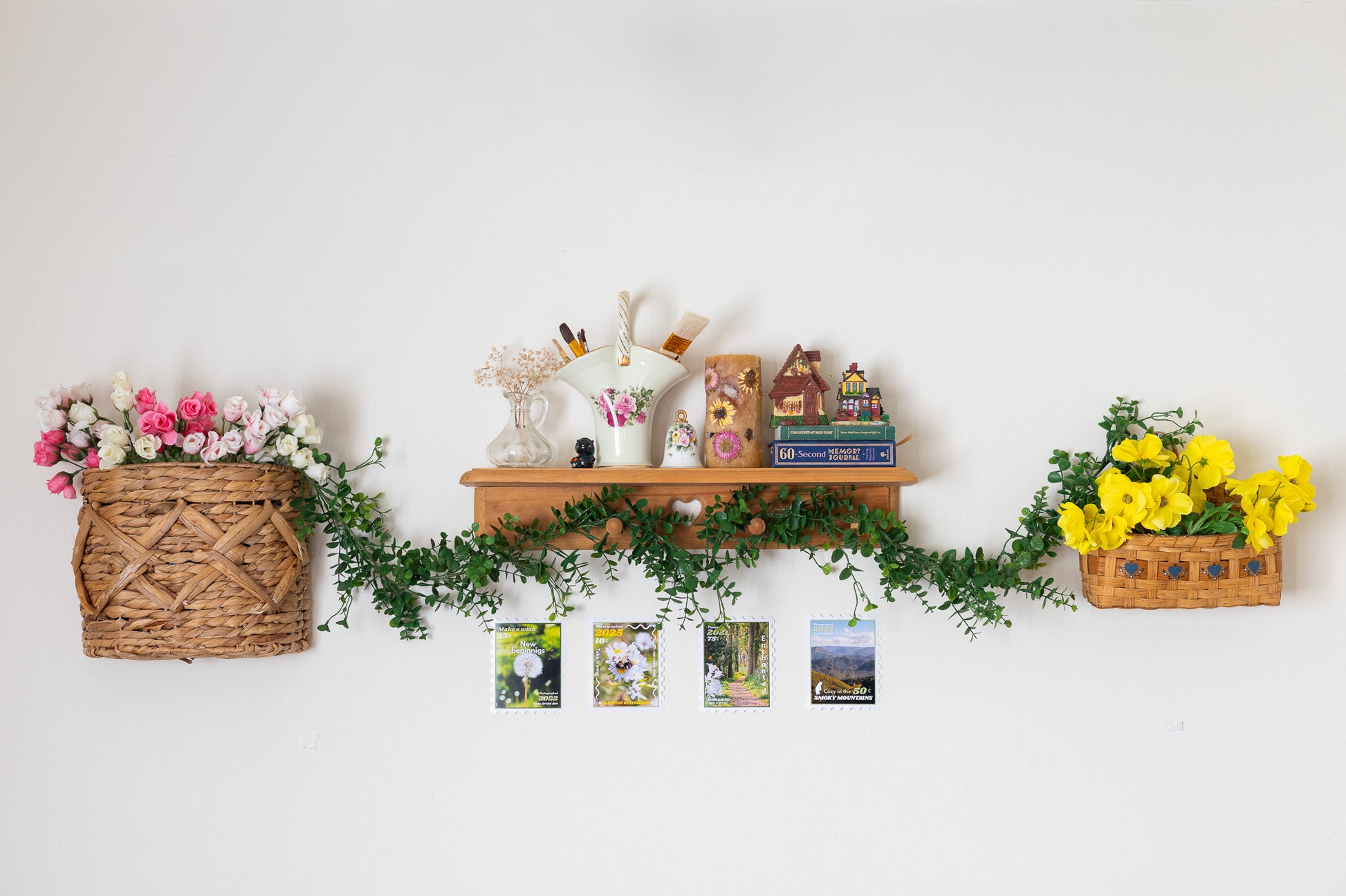 Decorative wall shelf with flowers, plants, and small items against a white wall.