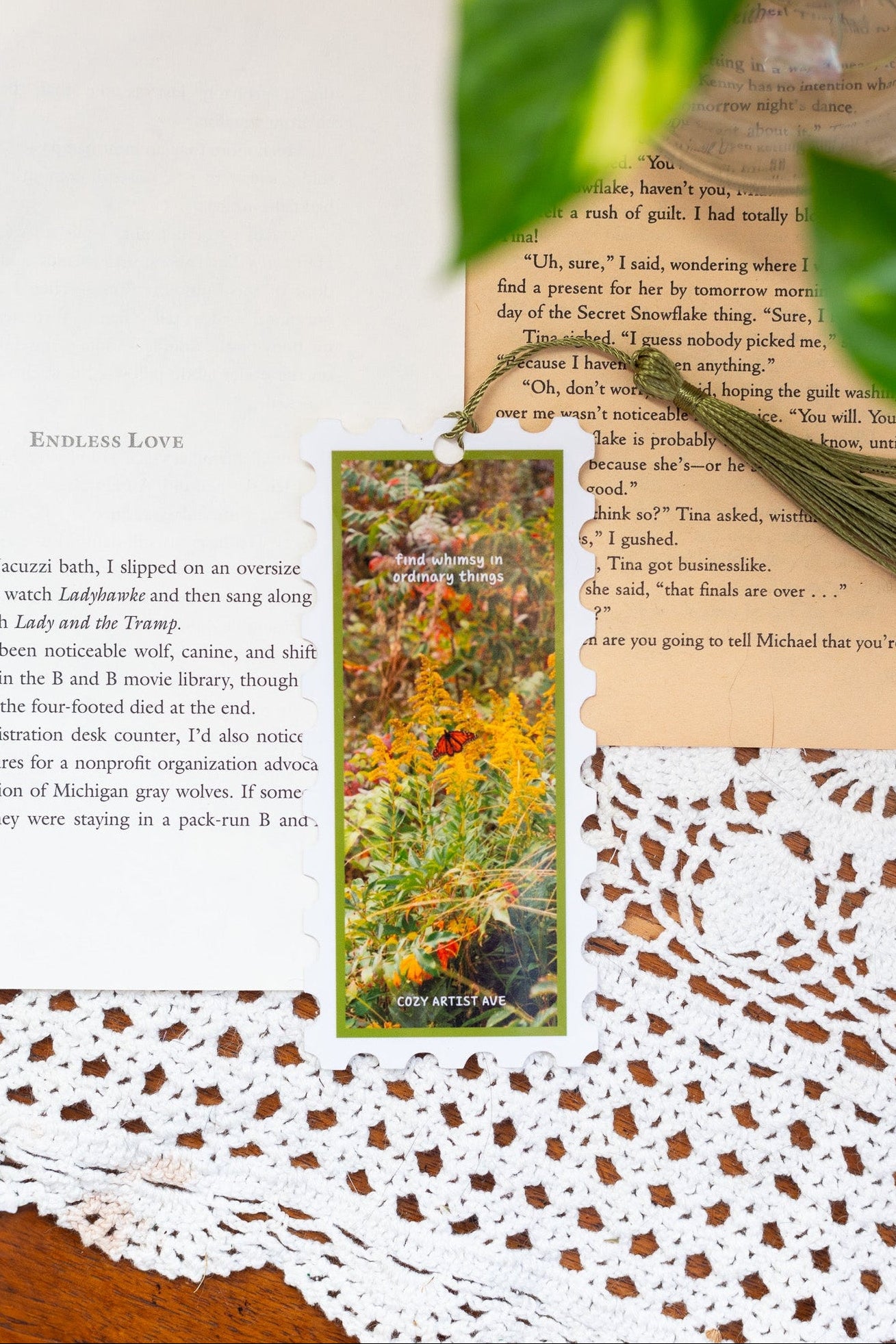 Scattered book pages with a tassel and nature-themed card on a textured surface.